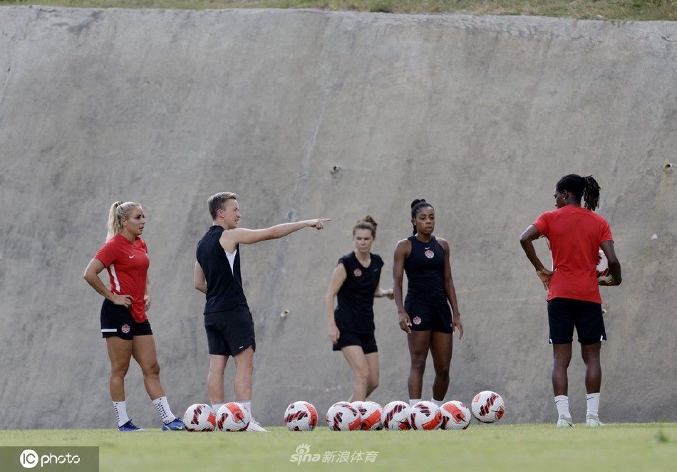 夕阳下的训练场，一名加拿大女足球员正奋力跃起争顶头球，身影在余晖中勾勒出力量的线条。