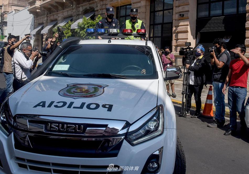 在亚松森一家酒店的阳台上，罗纳尔迪尼奥身穿深色便装，头戴黑色贝雷帽，双手轻扶栏杆，目光深邃地望向远方，这是他最后一次以被监禁者的身份俯瞰这座城市。