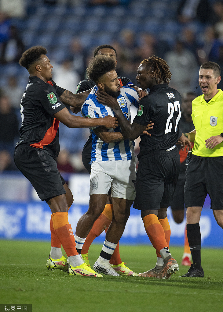 哈德斯菲尔德后卫汤姆·里斯在人群中高高跃起，一记强有力的头球攻破了埃弗顿的球门，他紧握双拳，脸上写满了坚定与激情，为球队扳平比分