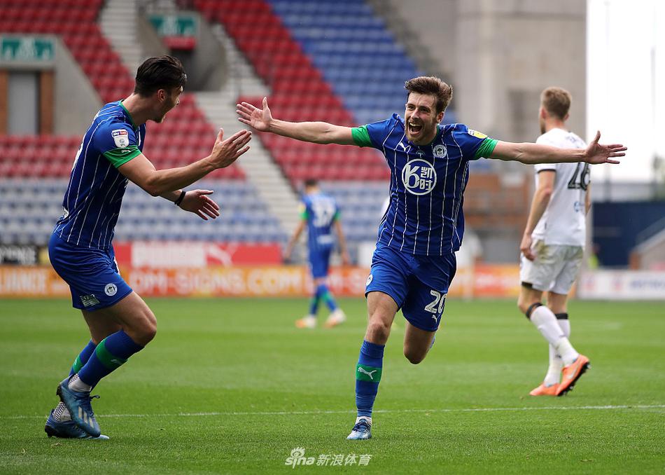 维冈竞技球员张开双臂在草地上肆意庆祝，背景是垂头丧气的赫尔城队员，巨大的记分牌上闪烁着8-0的刺眼比分，喜悦与绝望在瞬间被永恒定格