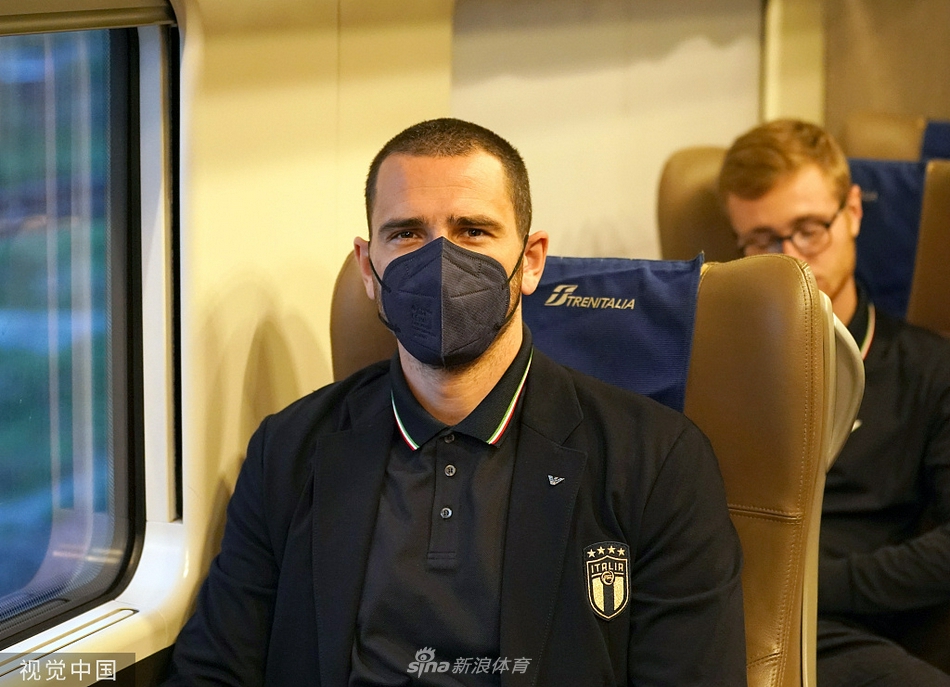 几位意大利队球员在登车前互相交流，其中一名球员手指前方，似乎在讨论着即将到来的征程与战术安排。