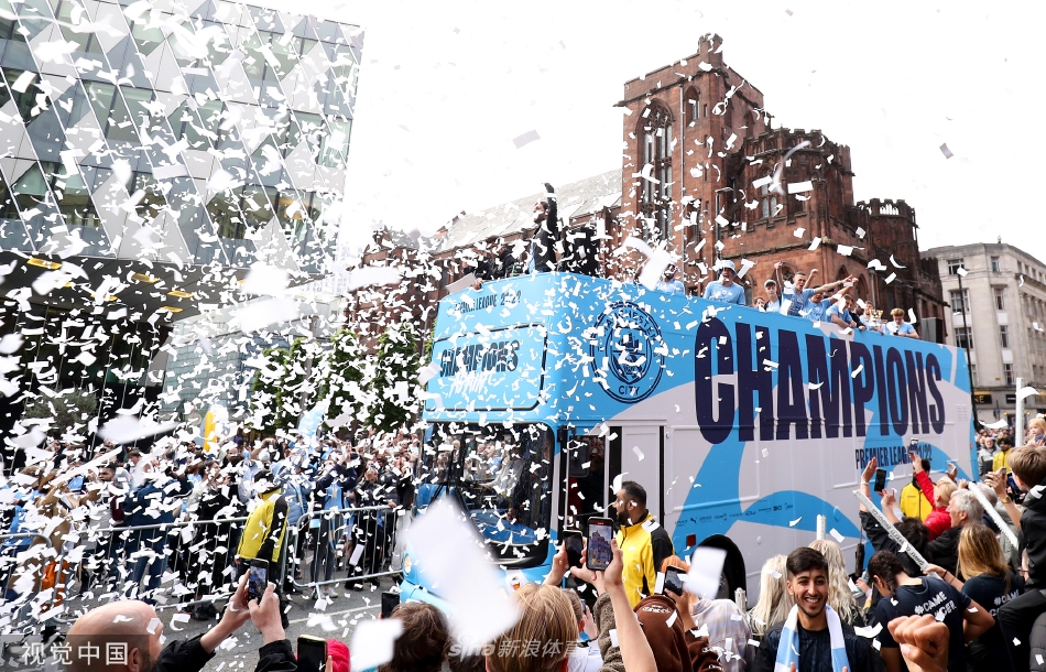 盛大的蓝色游行队伍如河流般蜿蜒穿过曼彻斯特古老的街道，两侧的建筑阳台与窗口挤满了挥舞旗帜的球迷，欢呼声浪直冲云霄。