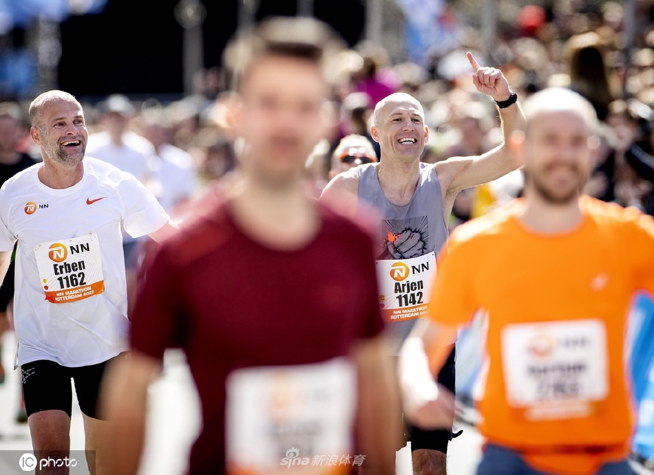 罗本在马拉松赛道中段奋力奔跑，步伐稳健有力，阳光洒在他汗水晶莹的脸庞上