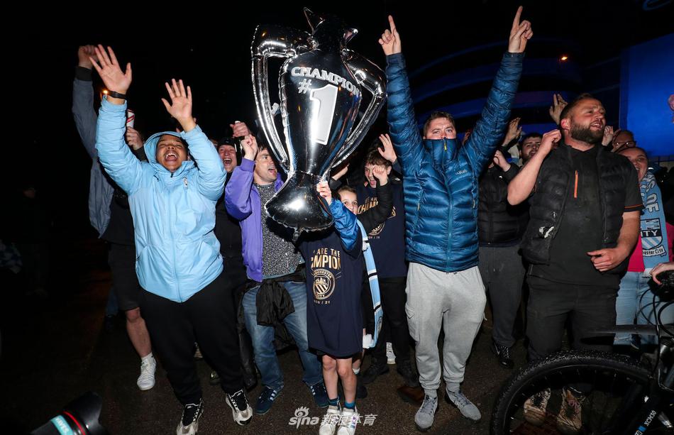 幾位年輕的球迷相互簇擁著自拍，他們的笑臉占據了整個畫面，背景是虛化了的伊蒂哈德球場和漫天藍色的燈光，他們的眼神中閃爍著對這支球隊無限的驕傲與熱愛。