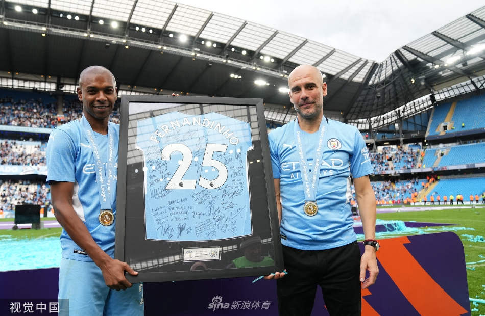 费尔南迪尼奥在队友簇拥下高举英超冠军奖杯，笑容灿烂，身后是漫天飞舞的蓝色彩带。