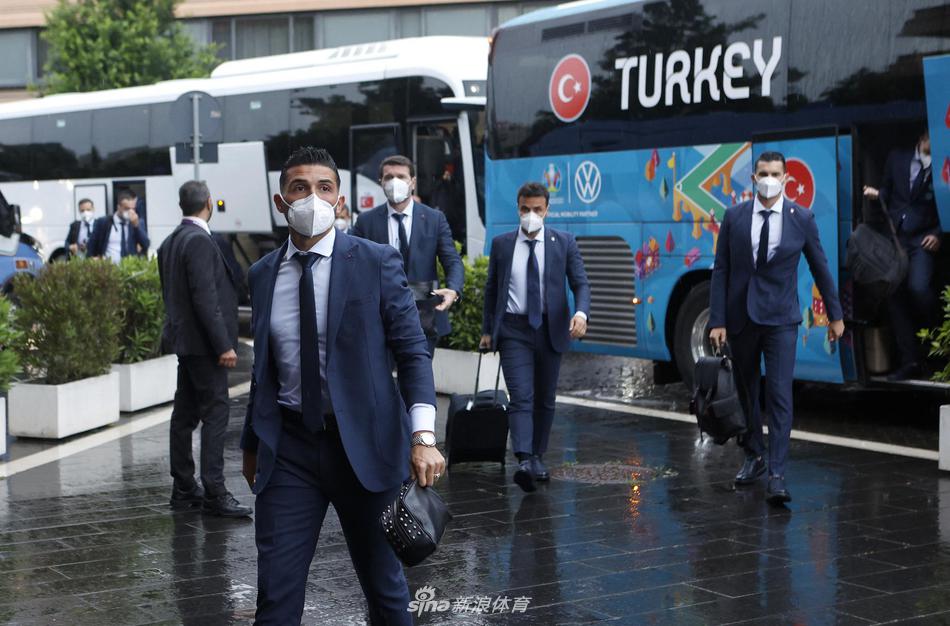 一群土耳其国家队球员在抵达酒店后，聚集在门口交流。背景是罗马古老的街道，球员们年轻的面孔与这座古老城市的背景交融，仿佛在诉说一段关于勇气与挑战的现代足球史诗。