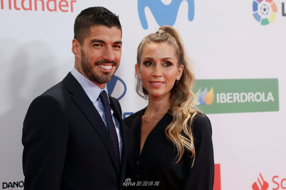 苏亚雷斯在颁奖礼现场与妻子索菲亚低头轻语，两人笑容满面，沉浸在喜悦与默契的氛围中，周围是璀璨的灯光与盛装的宾客