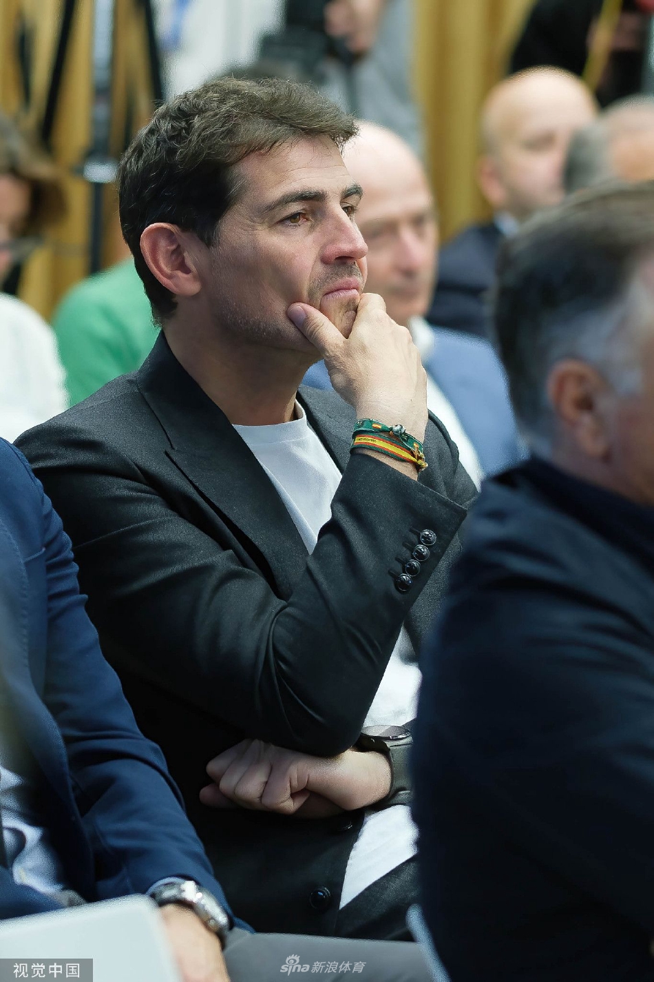 传奇门神圣卡西利亚斯单膝跪地，专注地为身前的小守门员调整手套，画面充满传承的温情与仪式感