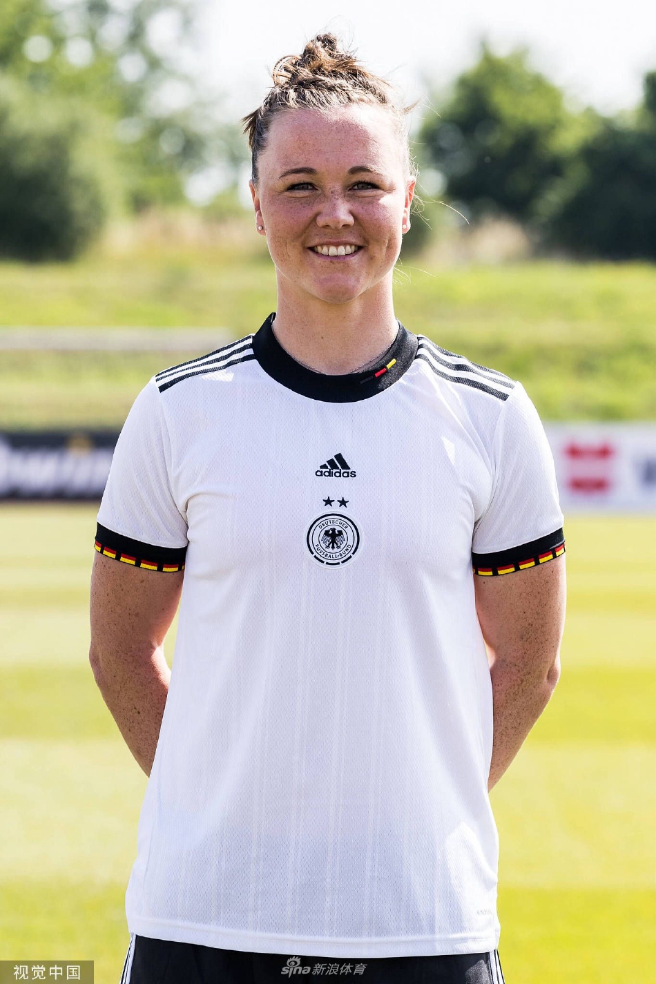 一名前锋球员手持足球特写，她嘴角微扬露出自信微笑，指尖轻抚球面，仿佛在无声诉说着对破门得分的渴望与娴熟技艺的掌控。