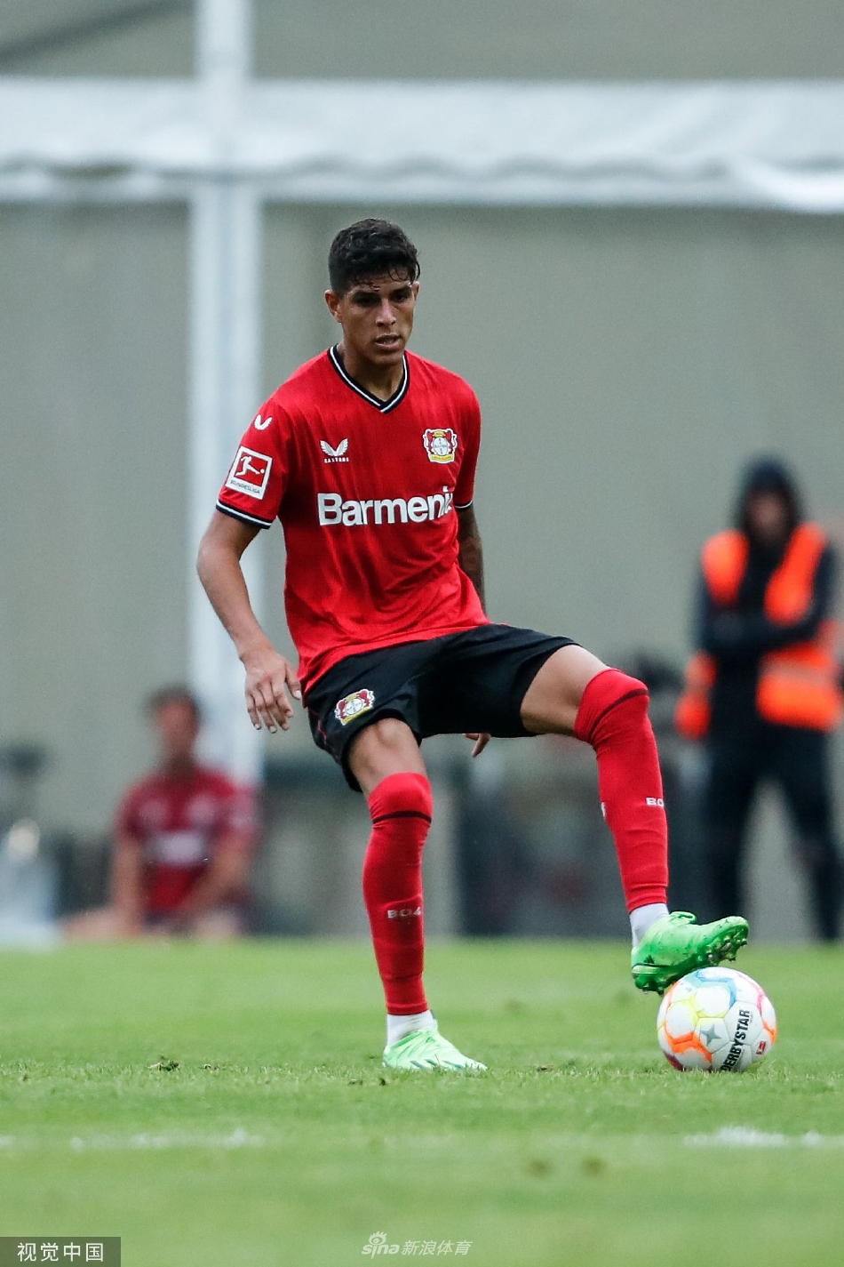 双方球员在中场激烈拼抢，草皮被鞋钉掀起，一名球员失去平衡倒地仍努力伸脚够球