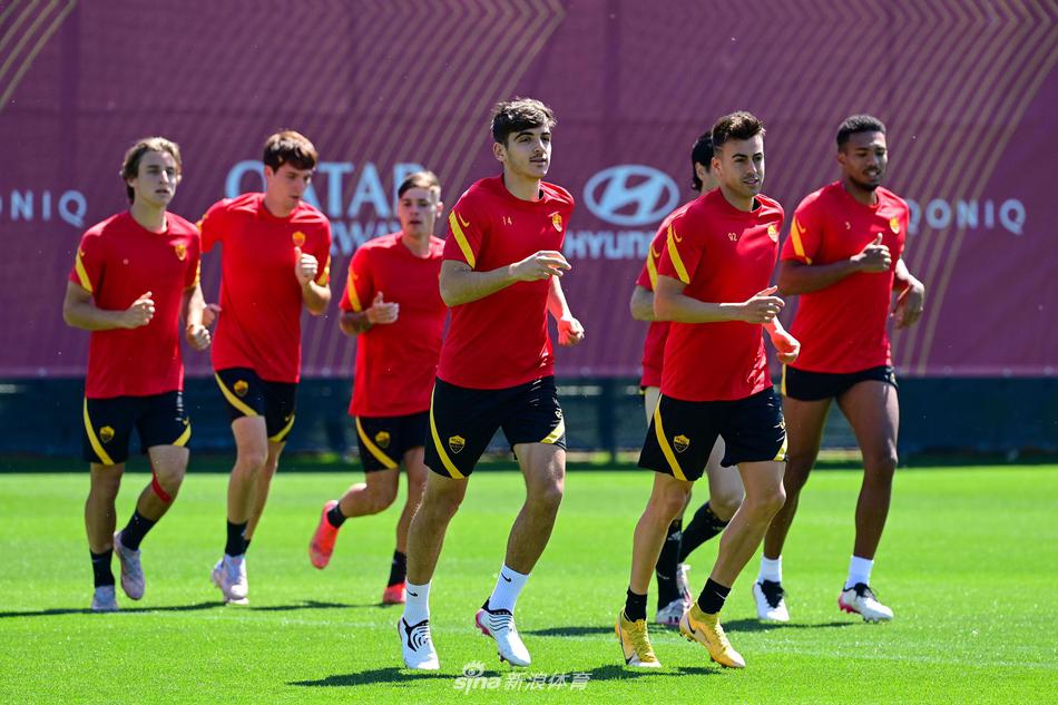 兄弟同心，训练结束后，两名罗马球员并肩走向场边，互相揽着肩膀低声交流，背景是逐渐亮起的球场灯光，友谊与团队精神在此刻凝固。