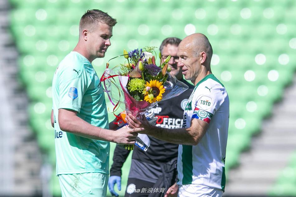 在气氛热烈的球场内，罗本伸出手臂，轻轻搭在队友帕特的肩上，两人并肩而行，身后是广告牌和看台上模糊的观众身影。罗本的眼神中充满鼓励与祝福，帕特则微微低头，怀抱着那束象征告别与感谢的鲜花，画面充满温情与淡淡的离愁。