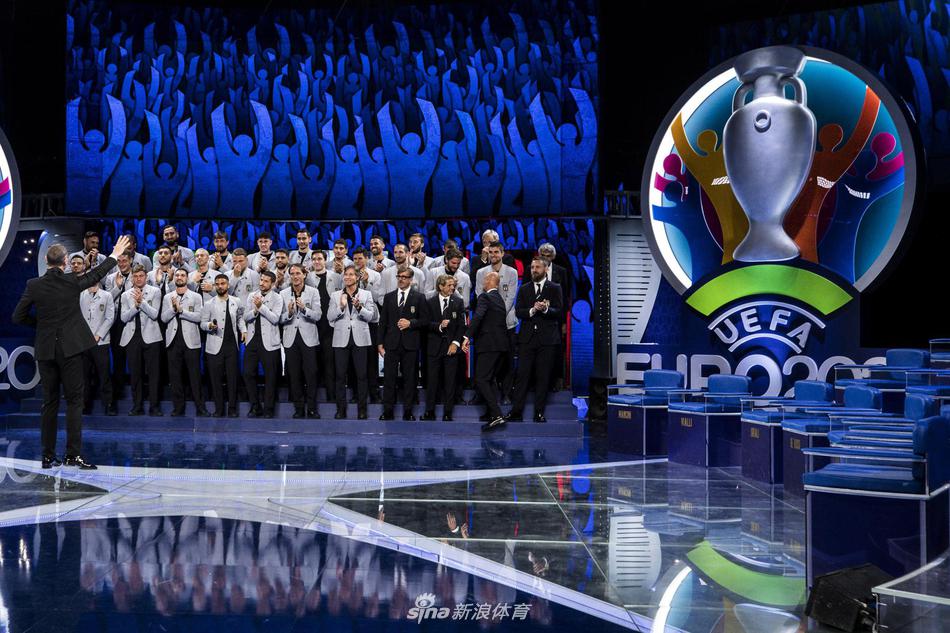 多纳鲁马、巴雷拉等年轻球员在后台休息区随意交谈，他们身着剪裁得体的浅灰色西装，脸上带着自信的笑容，尽显青春帅气的活力