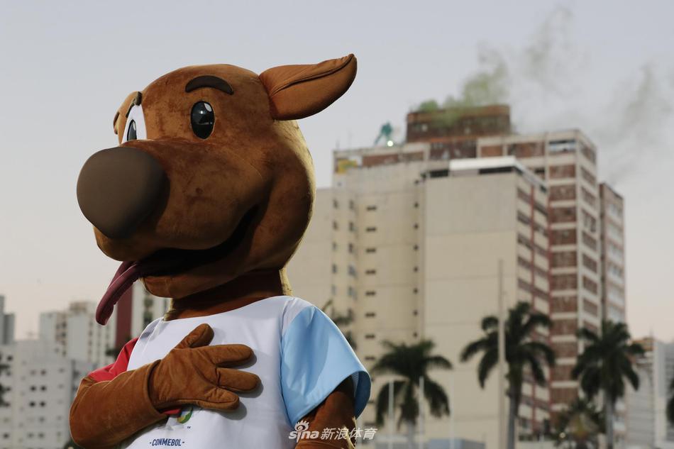 吉祥物兴奋地挥舞着双臂，迈开小短腿在球场边奔跑，像一个刚刚学会走路就迫不及待要上场踢球的孩子，浑身散发着无忧无虑的快乐气息。