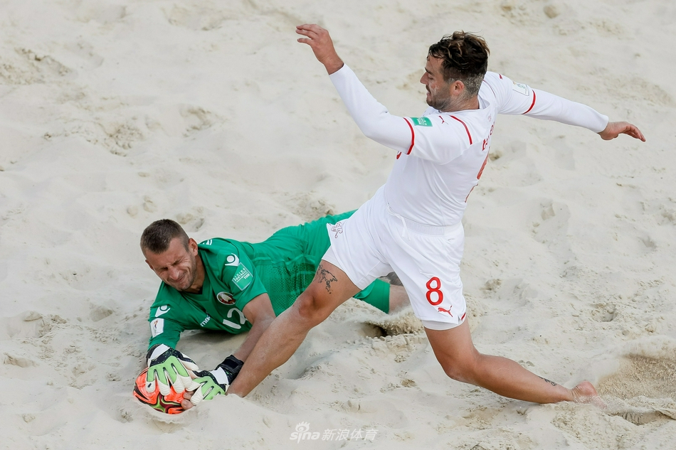 瑞士球员在拼抢中高高跃起，身体在蓝天白云下舒展，脚下的沙粒被阳光照耀得闪闪发光，充满了力量与美感