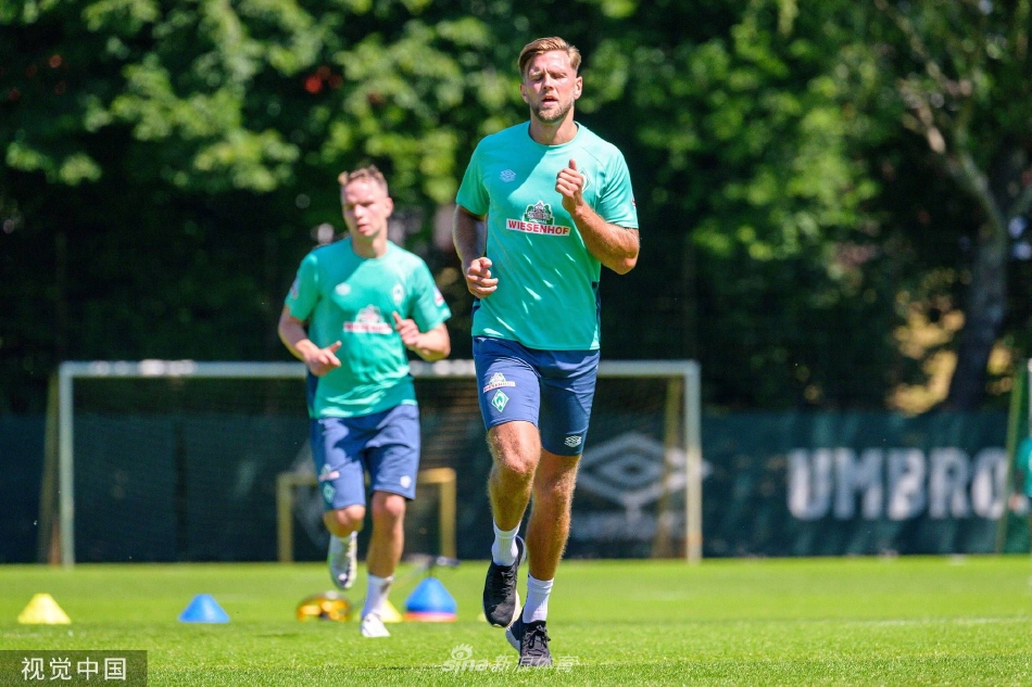 球队围成一圈进行战术部署，核心球员尼克拉斯·菲尔克鲁格位于中央，神情专注