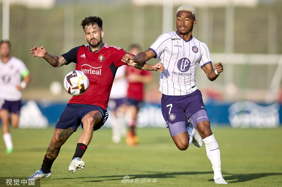 图卢兹球员在奥萨苏纳严防下精巧挑传，皮球划出美妙弧线越过防守队员头顶。