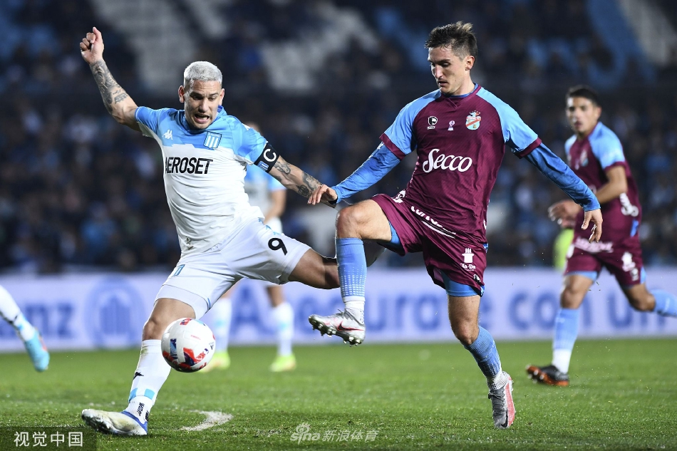 竞技队前锋在对方禁区前沿灵巧转身，两名防守球员如影随形形成夹击之势