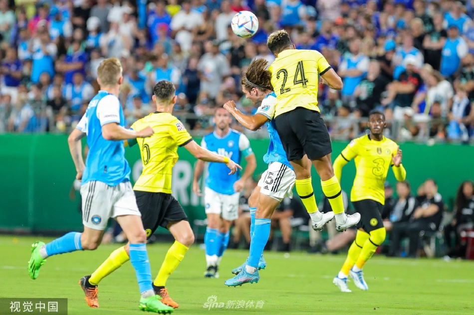 看台上切尔西与夏洛特FC球迷相邻而坐，蓝旗与紫旗交相辉映，构成和谐多彩的观众席画卷