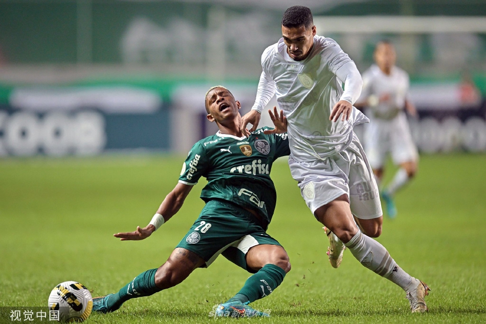 夕阳余晖下，一位球员孤独地坐在草皮上，背影透露出比赛失利后的疲惫与失望