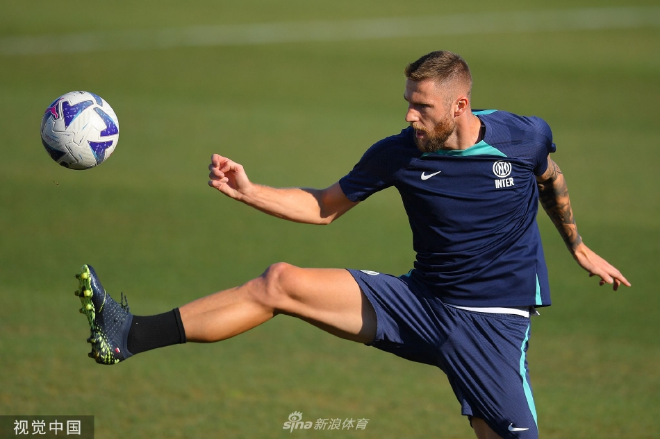 球队助理教练带领一组球员在边路进行折返跑体能训练，队员们肌肉线条分明，在夕阳的映照下奋力冲刺，汗水挥洒在草坪上。