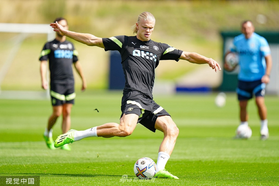 两名球员在阳光下认真进行一对一攻防演练，影子被斜阳拉长印在草皮上