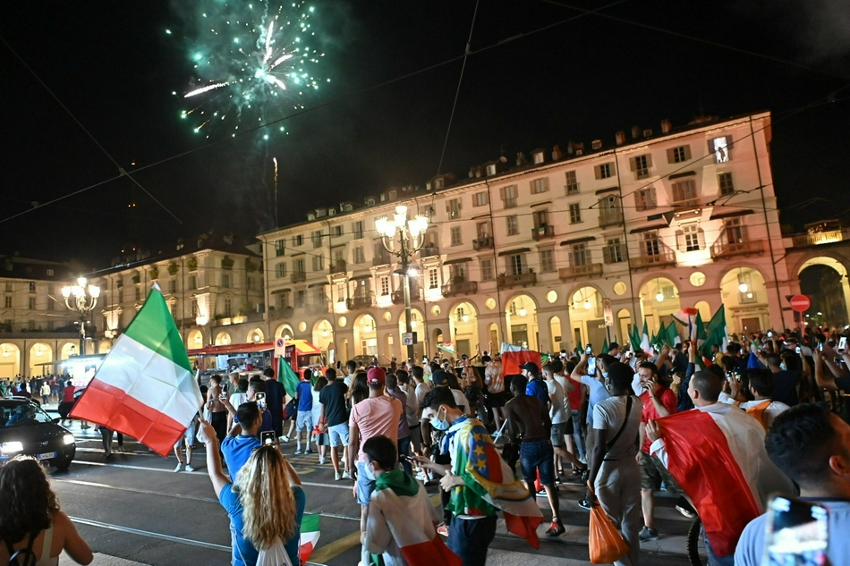 夜幕下的都灵城被蓝色的烟雾弹笼罩，无数意大利国旗在街头飘扬，庆祝的人潮如海浪般涌动，整座城市化身为一片沸腾的蓝色海洋。