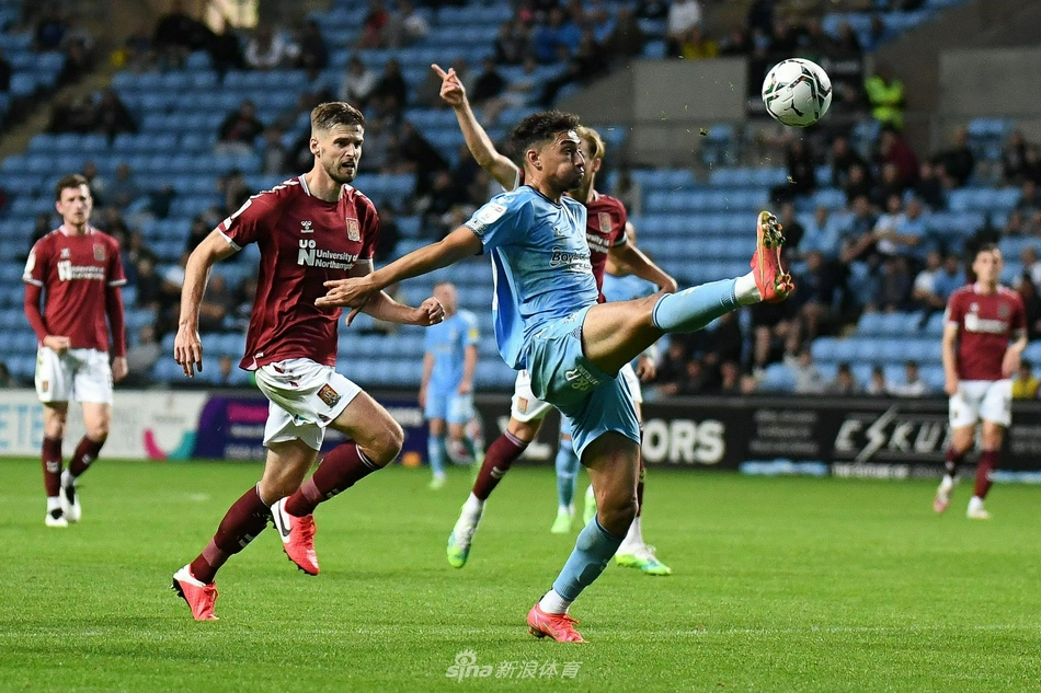 进球后的北安普顿球员张开双臂，尽情享受着客场逆转带来的荣耀时刻，他的身后是神情落寞的考文垂防守队员。