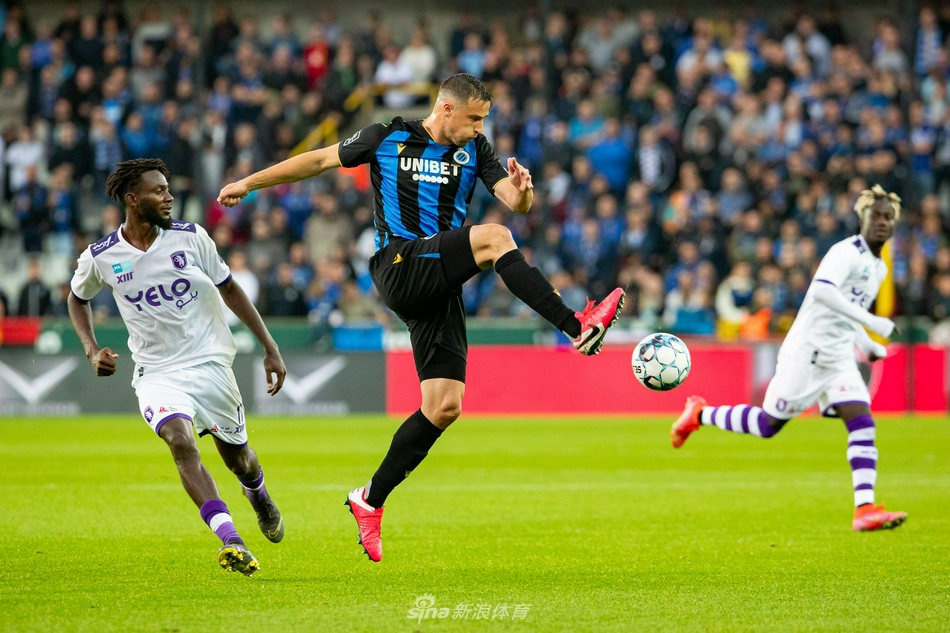 比尔肖特前锋在布鲁日禁区内奋力争顶，他高高跃起，身体在空中形成一道弓形，眼神紧紧锁定飞来的皮球，尽管身旁有防守球员干扰，但他依然全力争取每一次机会。