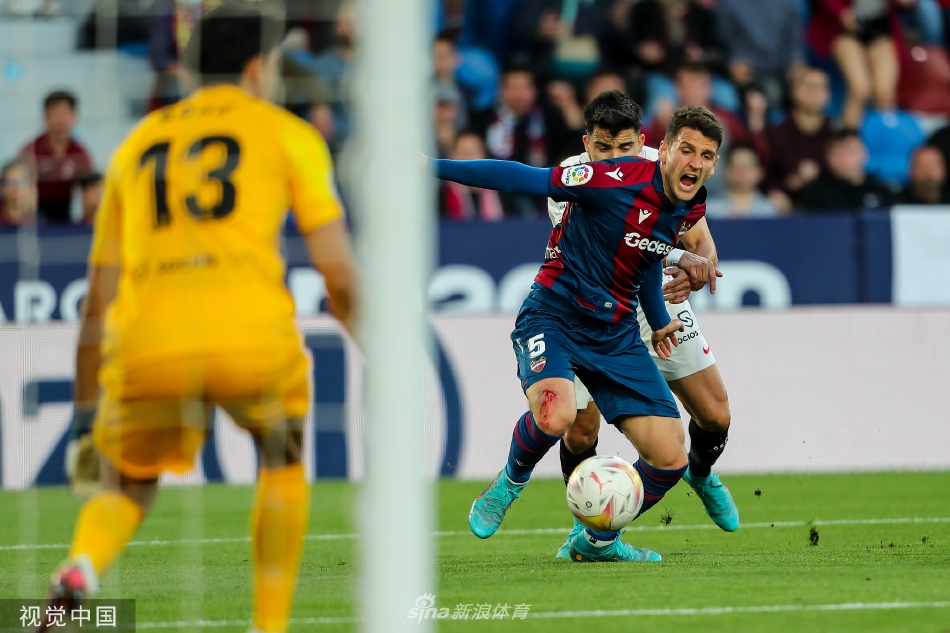 塞维利亚球员赫苏斯·科罗纳在进球后张开双臂，与助攻的队友奥坎波斯激情庆祝，背景是失望的莱万特门将与看台上喧嚣的球迷。