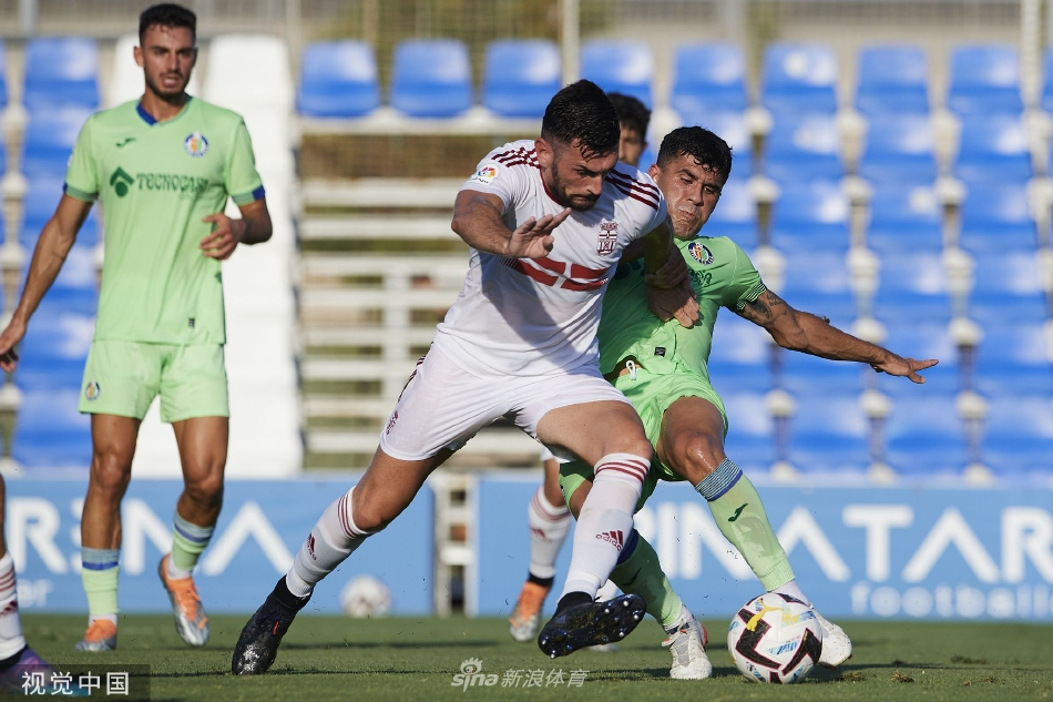 双方球员在中场展开激烈空中争顶，夕阳余晖勾勒出他们奋力跃起的矫健身姿