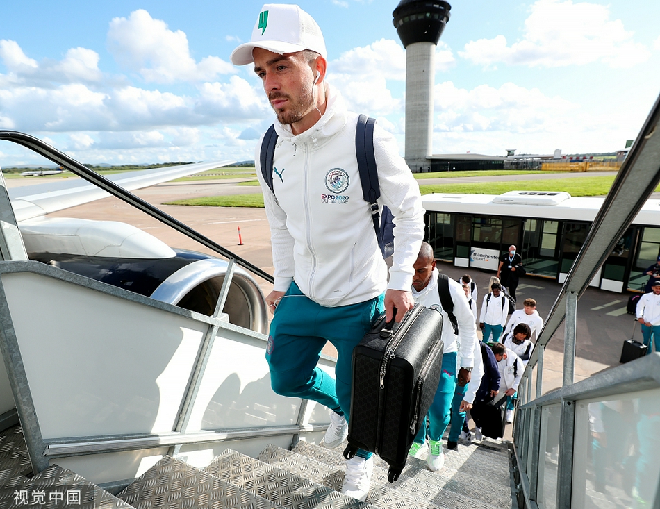 主帅瓜迪奥拉手提行李包走出航站楼，表情严肃地打着电话，似乎在确认最后的战术布置或球员身体状况，身姿依然保持着一贯的儒雅与干练。