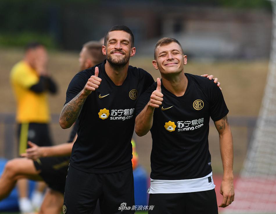 在德国午后的阳光下，孔蒂双手插兜站立场边，目光如炬地注视着弟子们的每一次传跑，他的剪影与远处的训练设施构成一幅专注的备战画卷。