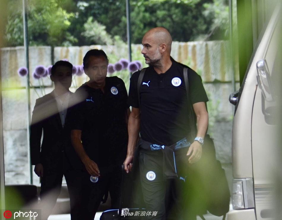 南京夏日，曼城天蓝色大巴静静停靠酒店门前，玻璃幕墙倒映着古城的天际线，仿佛宣告着英超冠军的东方之旅正式拉开序幕。