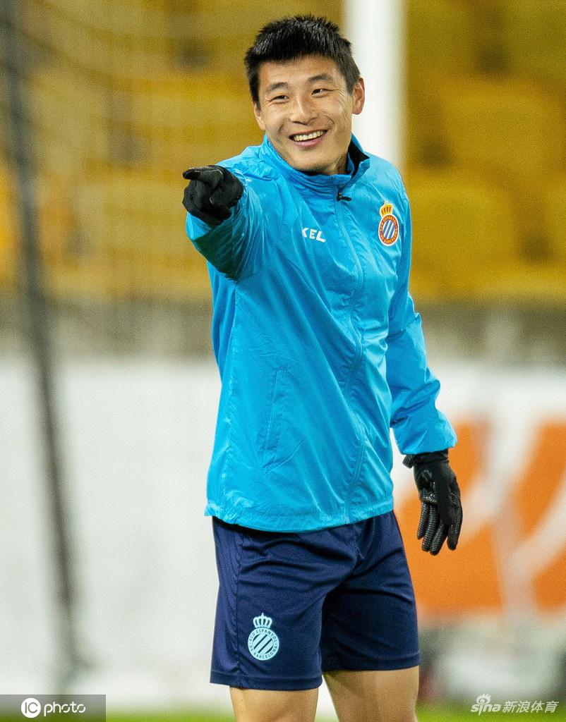 武磊俯身系鞋带，眼神却专注地凝视着远处的训练目标，仿佛在积蓄力量，随时准备在比赛中一鸣惊人。