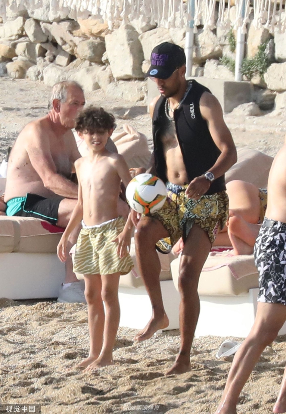 奥巴梅扬父子并肩而立眺望大海，脚下踩着足球，画面充满传承与未来的象征意义