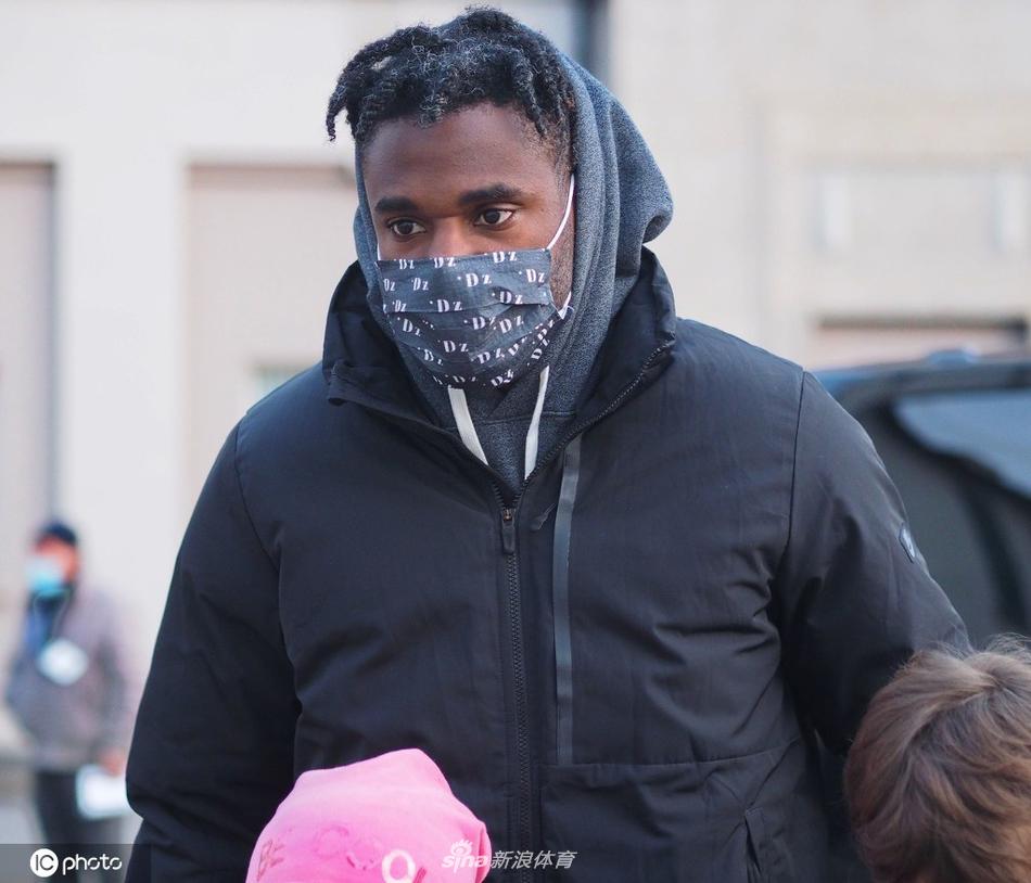 夜幕下的球场灯光如昼，一位小球迷终于拿到了宝贵的签名，他心满意足地低头审视着这份礼物，身旁的大人则为他记录下这一生难忘的追星瞬间。