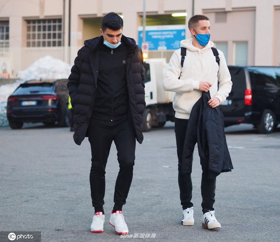 一名亚特兰大球员弯下高大的身躯，他戴着口罩，眼神专注而温柔，正在一件蓝色球衣上认真地签下自己的名字，旁边的小球迷则紧张又期待地注视着这一切。