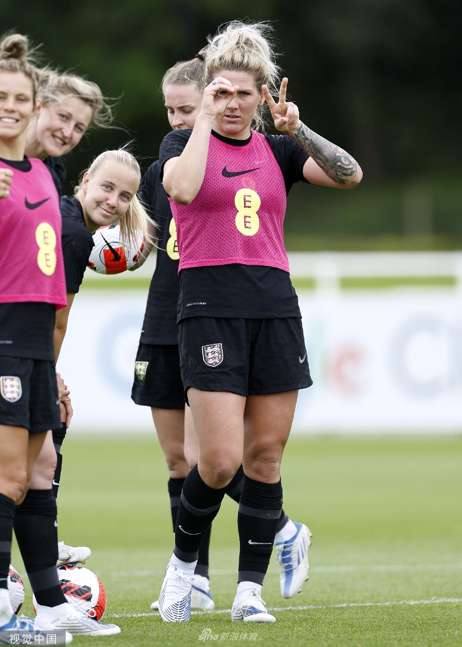 英格兰女足队长莉亚·威廉森在训练中微笑着与队友交流，眼神坚定而充满感染力。