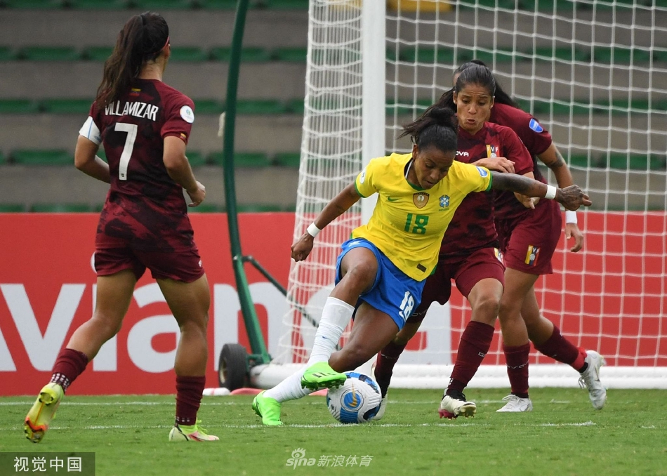 巴西中场核心阿德里亚娜带球高速突破，两名委内瑞拉防守球员左右夹击，三人身影在绿茵场上交织成一幅动态十足的对抗画面。