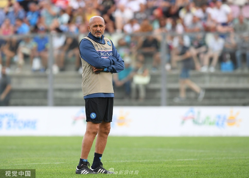 训练间歇，两名那不勒斯球员坐在草地上轻松交谈，露出笑容，展现了团队内部轻松融洽的氛围。