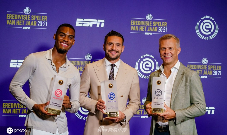 在聚光灯的照耀下，阿贾克斯队长神情庄重地举起象征着荷甲最高荣誉的冠军奖盘，金色的纸屑在空中飞舞，仿佛在为他们的加冕仪式献上最热烈的祝贺。