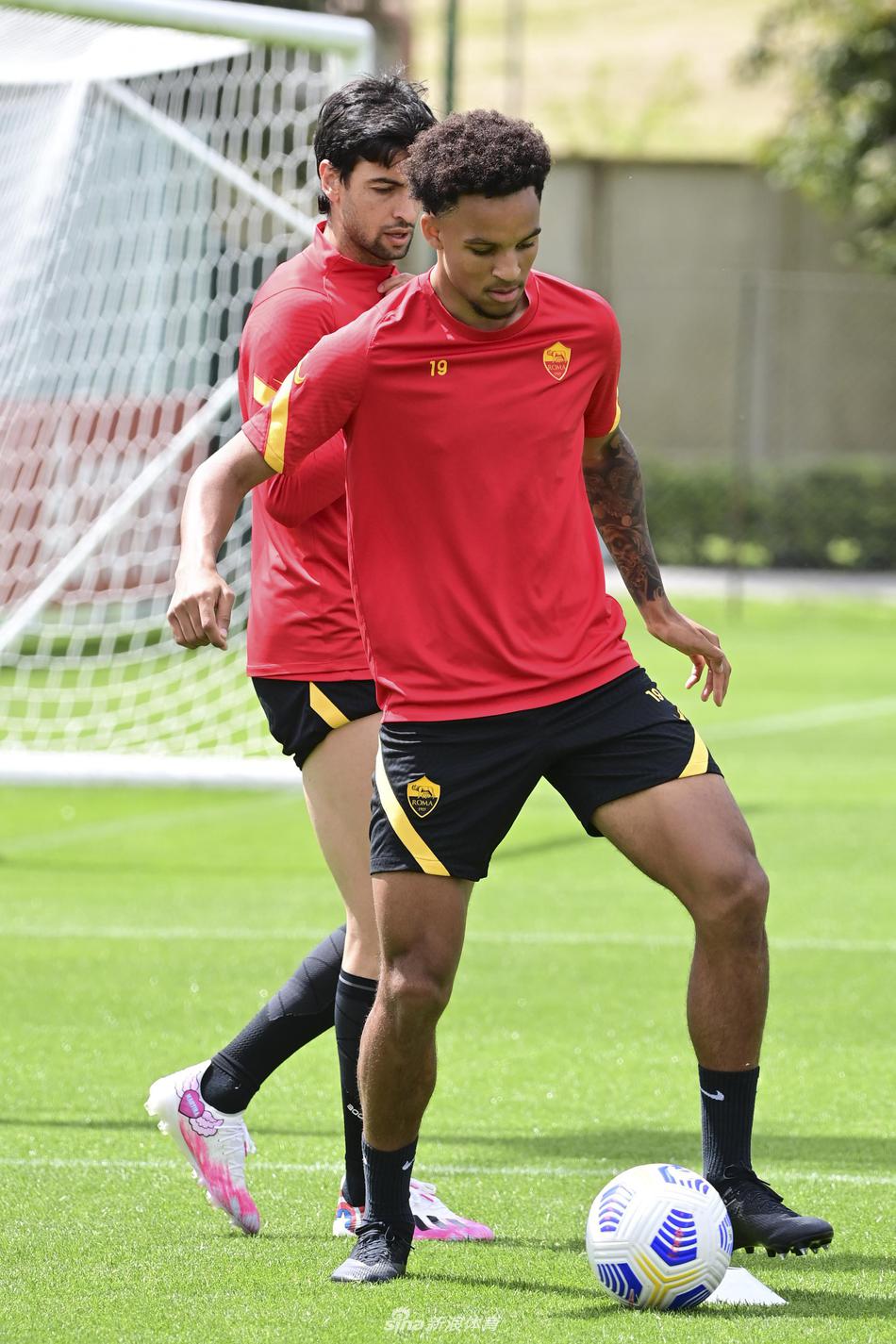 守门员在教练的辅助下进行高难度扑救训练，他飞身跃起，身体舒展到极致，指尖即将触碰到飞速而来的皮球。