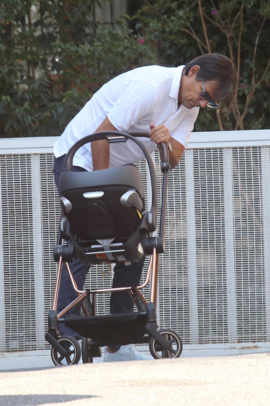 妻子盖娅·卢卡列洛走在身侧，浅蓝色连衣裙随风轻摆，她低头看向婴儿车，一家三口的温馨互动让午后的罗马街道流淌着无声的爱意。