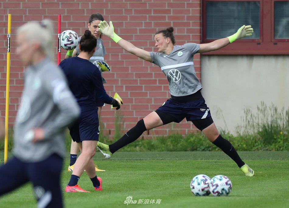 主教练在场边双手比划着战术，眼神专注而深邃。他的身后是沃尔夫斯堡宏伟的球场看台，空旷的座位仿佛在等待明日胜利后的欢呼。