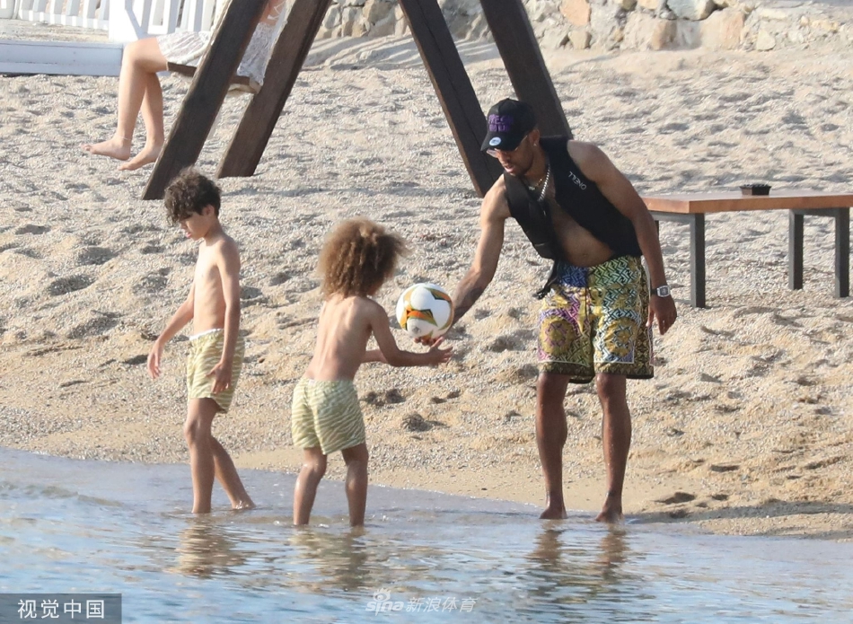 奥巴梅扬微笑着展示脚背颠球技巧，儿子在一旁聚精会神地观察，足球在空中划出优雅的弧线