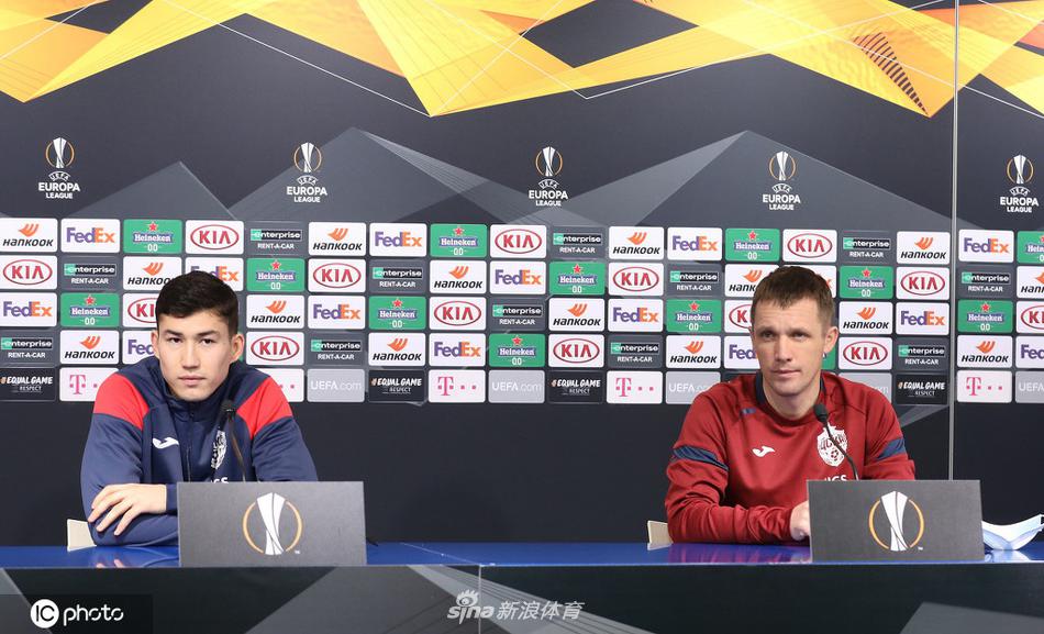 发布会桌前话筒林立如枪阵，主帅沉稳手势勾勒战术蓝图，背景板上的陆军徽章在闪光灯下折射出战斗民族的不屈。