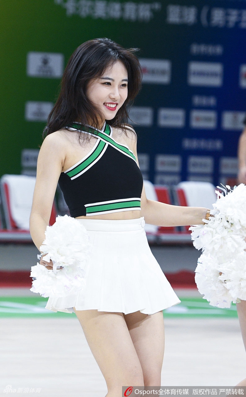 侧身回眸的拉拉队员展现出优美的身体曲线，飘逸的长发与动感的舞姿定格在这一瞬，背景是虚化的全运会场馆和热情欢呼的观众。