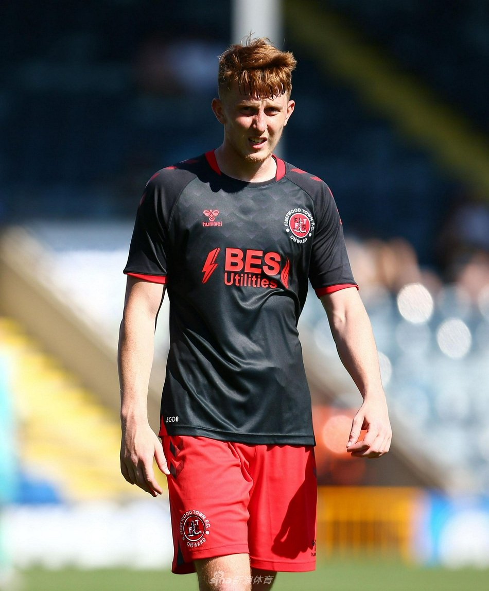 福利特伍德后卫奋不顾身地滑铲，试图阻挡罗奇代尔前锋的突破，皮球在两人之间即将发生变向，飞溅的草屑记录了这次防守的激烈程度。