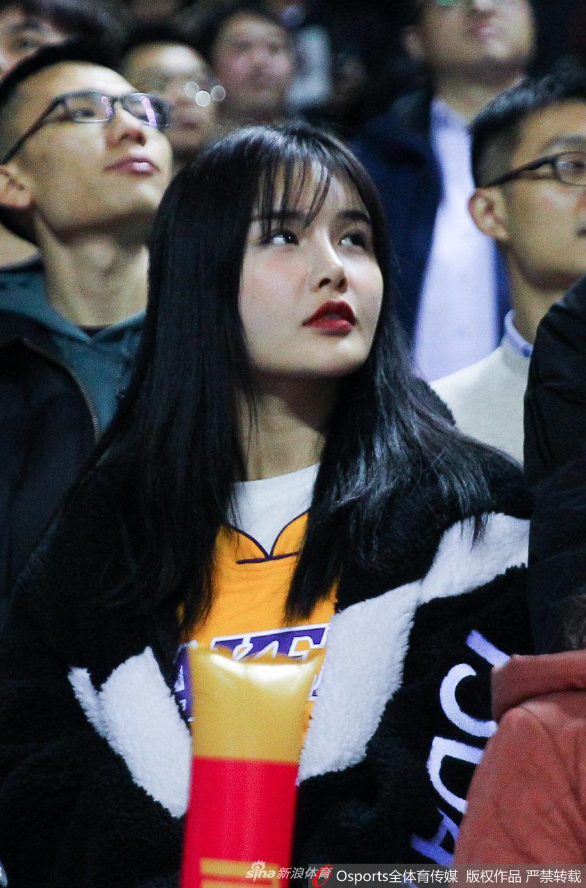 小球童调皮地模仿着吉祥物的动作，巨大的玩偶服与娇小的身躯形成鲜明对比，逗乐了旁边正在热身的工作人员。